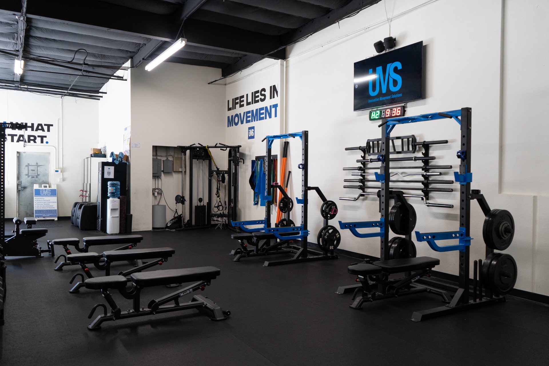 Squat racks beneath the Life Lies In Movement wall at IMS